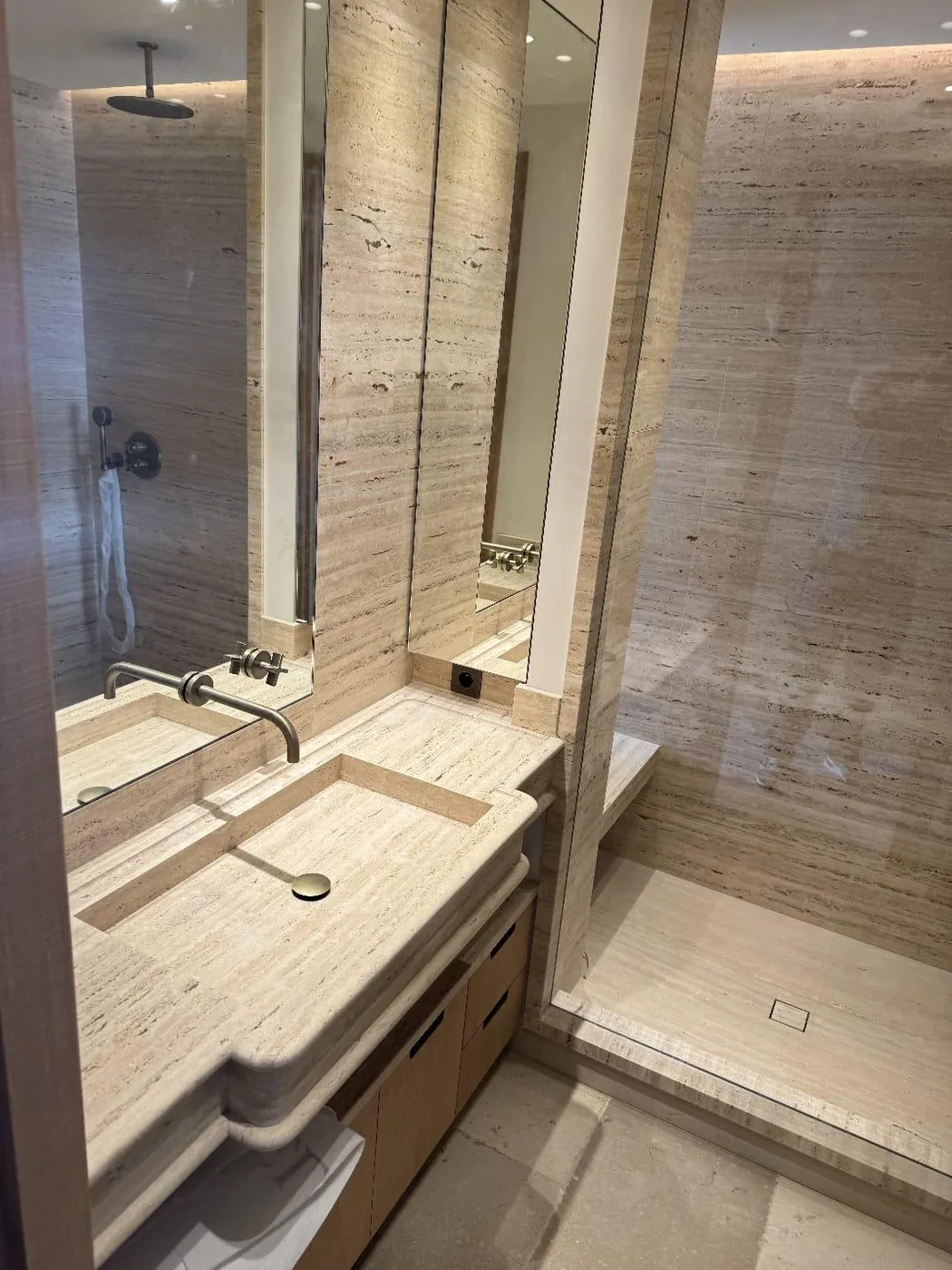 Salle de bain en travertin, vasque encastrée et grand miroir